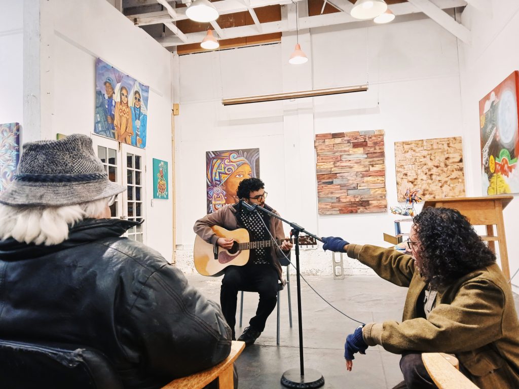 Medicine for Nightmare's Josiah Alderete holds the microphone for an open mic performer with a guitar